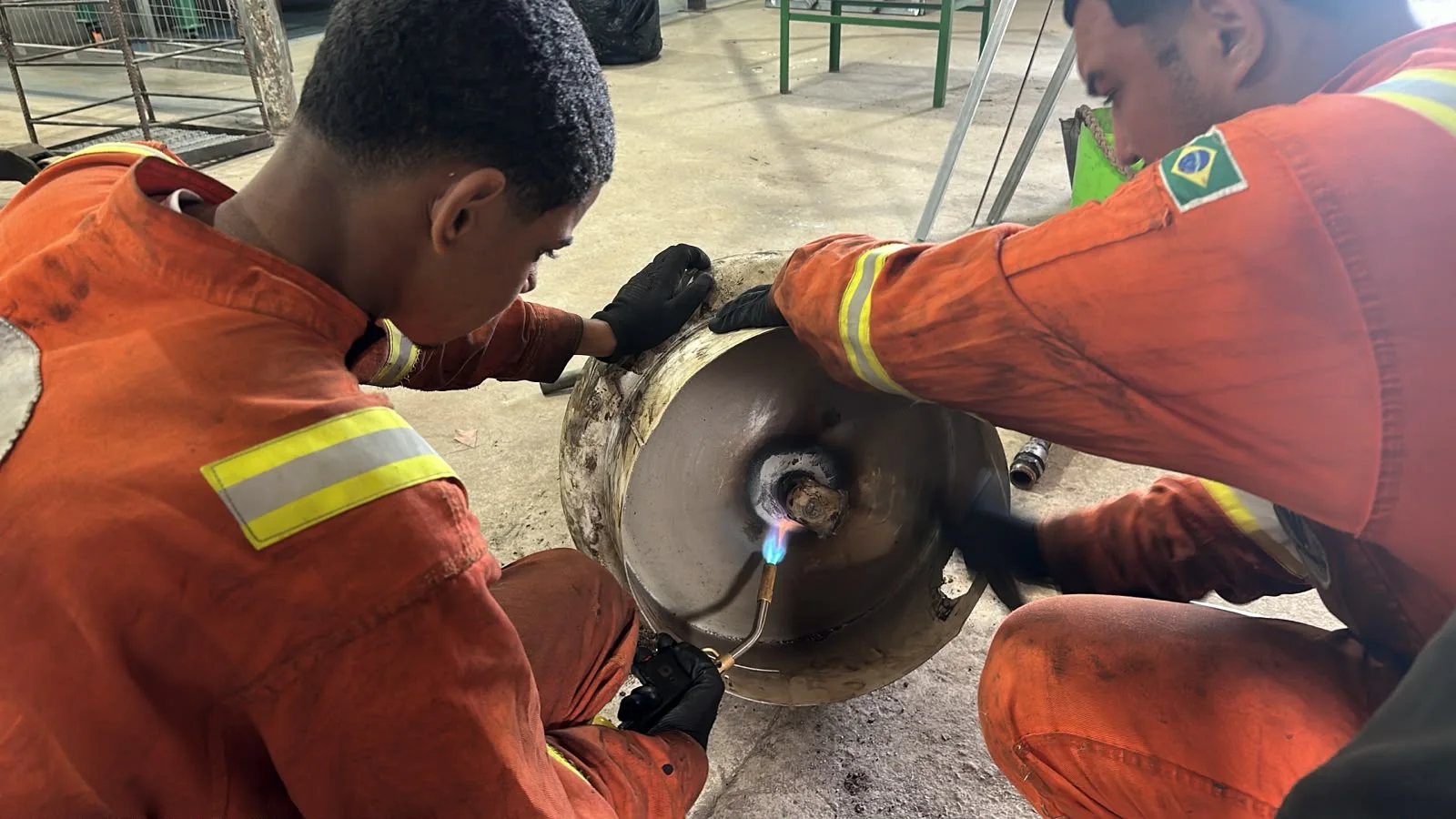 Two WF Service technicians heating a cylindrical component with a torch