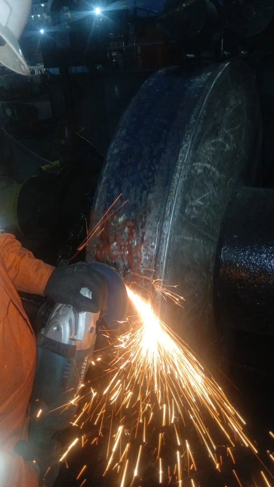 Grinding a large industrial component, throwing a spray of sparks